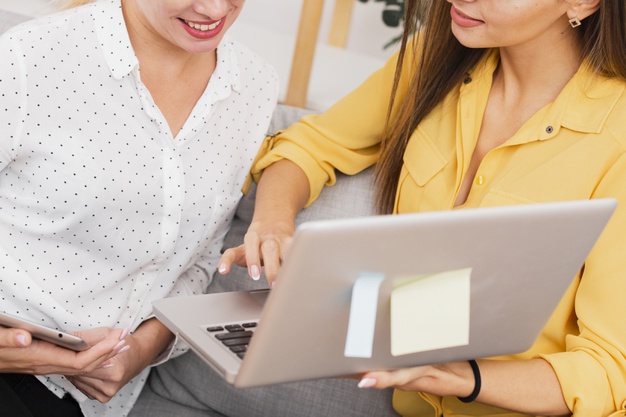 Gestão Integrada - Paromed: Duas mulheres conversando, uma mostra a tela do notebook para a outra que está sorrindo