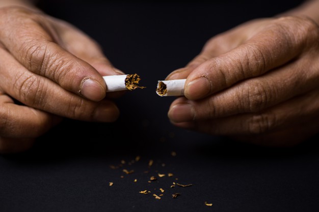 mão rasgando cigarro ao meio