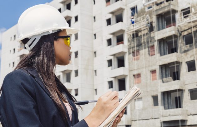 mulher em construção, anotando para produzir um planejamento de sst